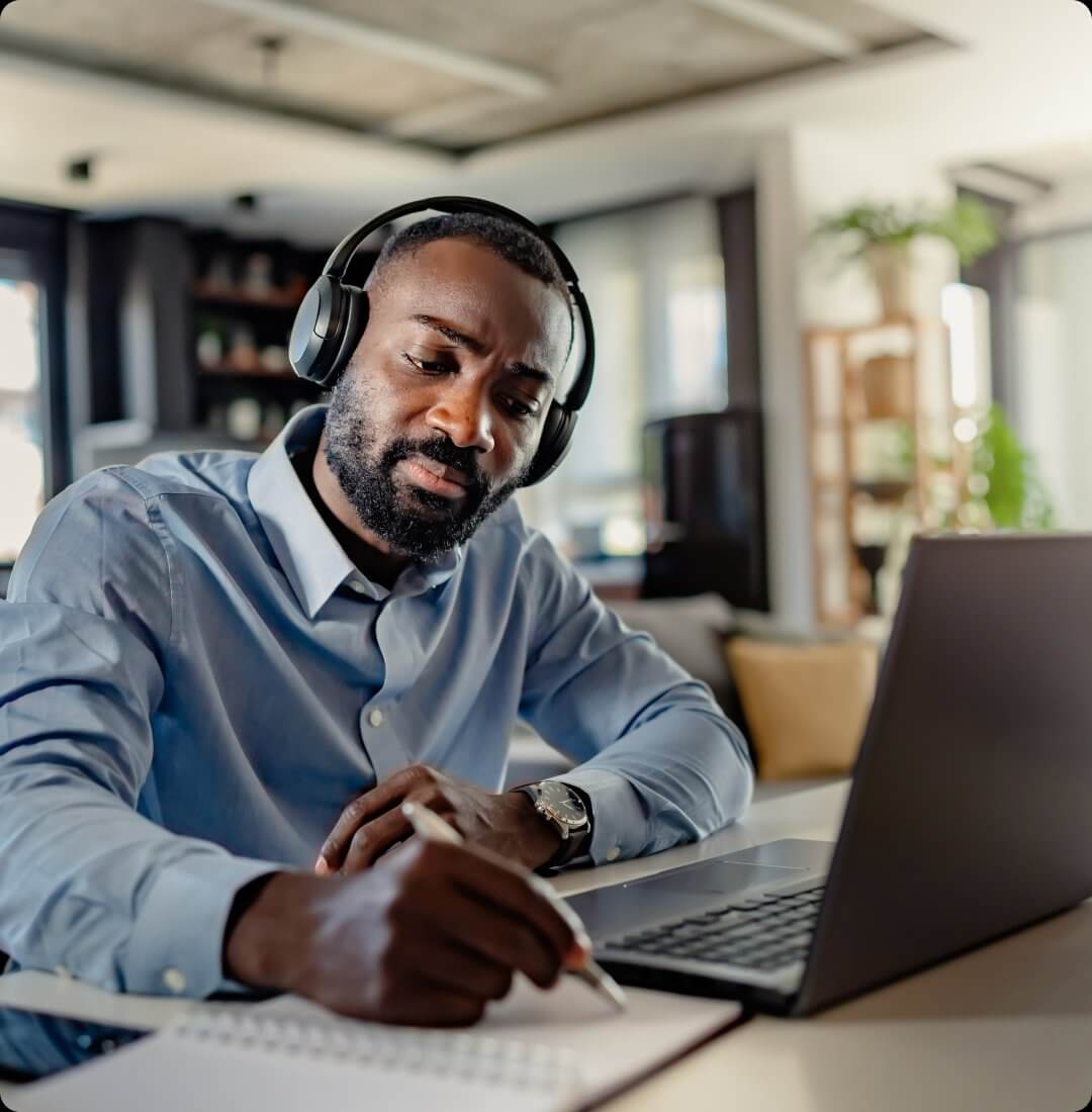 Remote worker with headphones using laptop at desk